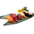 A close-up shot of a Naeki's sushi platter on a green bamboo leaf. The platter includes a variety of nigiri and maki sushi, such as salmon nigiri, tuna nigiri, shrimp nigiri, and salmon maki rolls. A yellow chrysanthemum and a sprig of green garnish are placed at the top right. The background is completely black, making the sushi stand out.